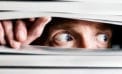 Scared man looking through slats of a blind Do you suffer from a false sense of no confidence?