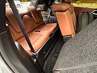 2026-Outlander-PHEV-seating - Strathmore Voice Cargo area of a car with orange-brown leather rear seats folded down, gray carpeting, and a visible seat belt.
